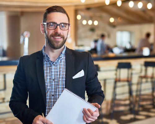 Businessman with notepad looking at camera in restaurant